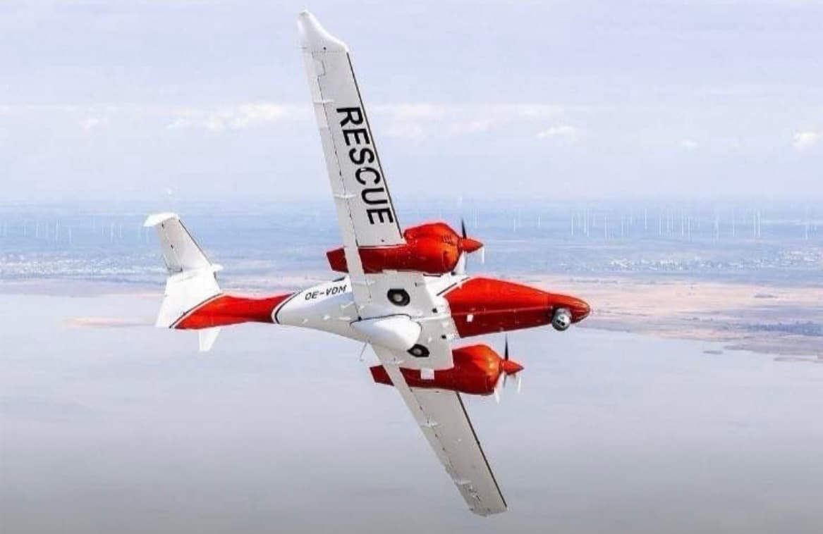 Diamond DA62 MPP search and rescue aircraft with red and white SAR livery over coastline
